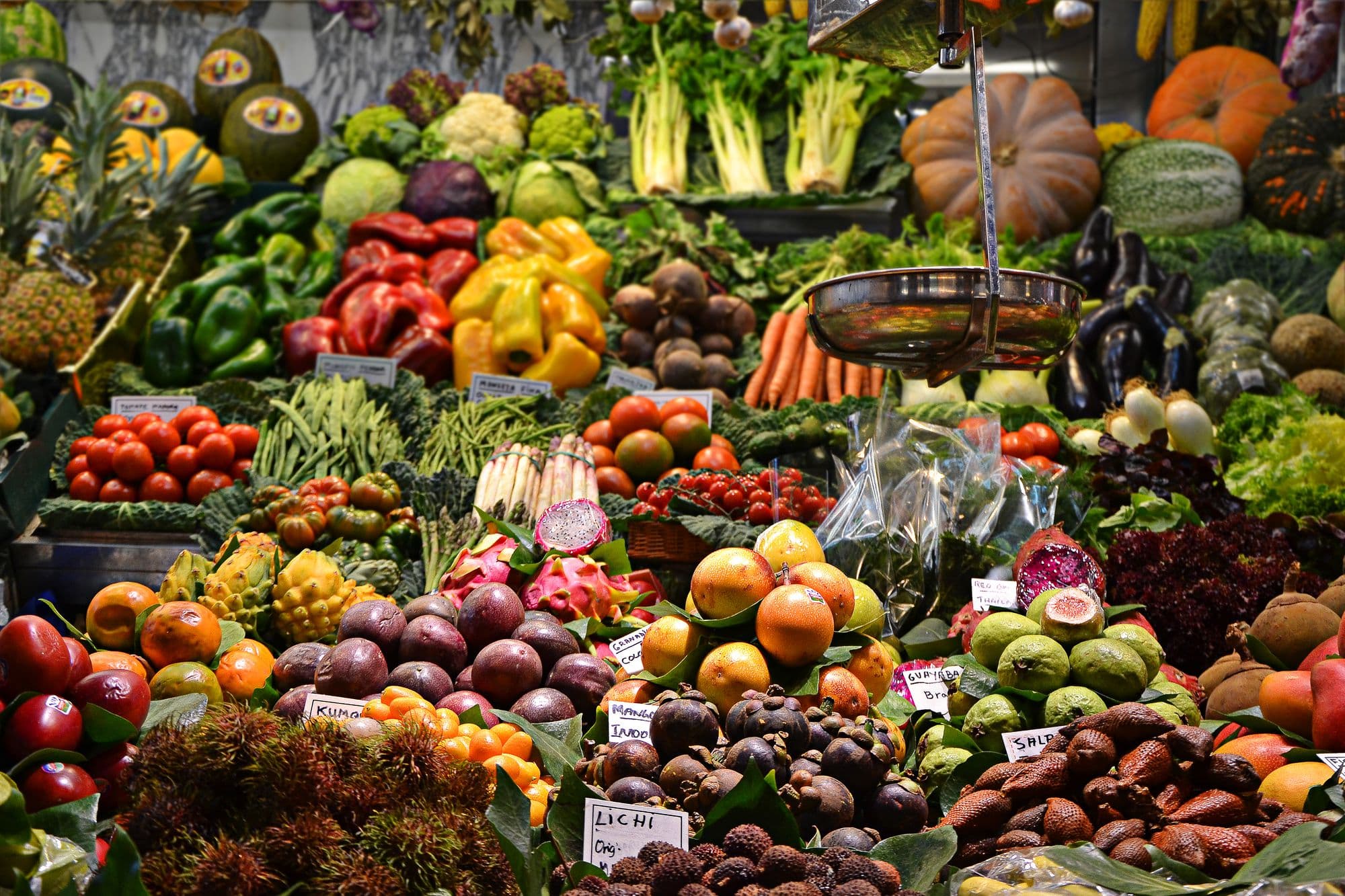 Banca de hortifrúti com pimentões, abóboras, tomates, frutas e verduras
