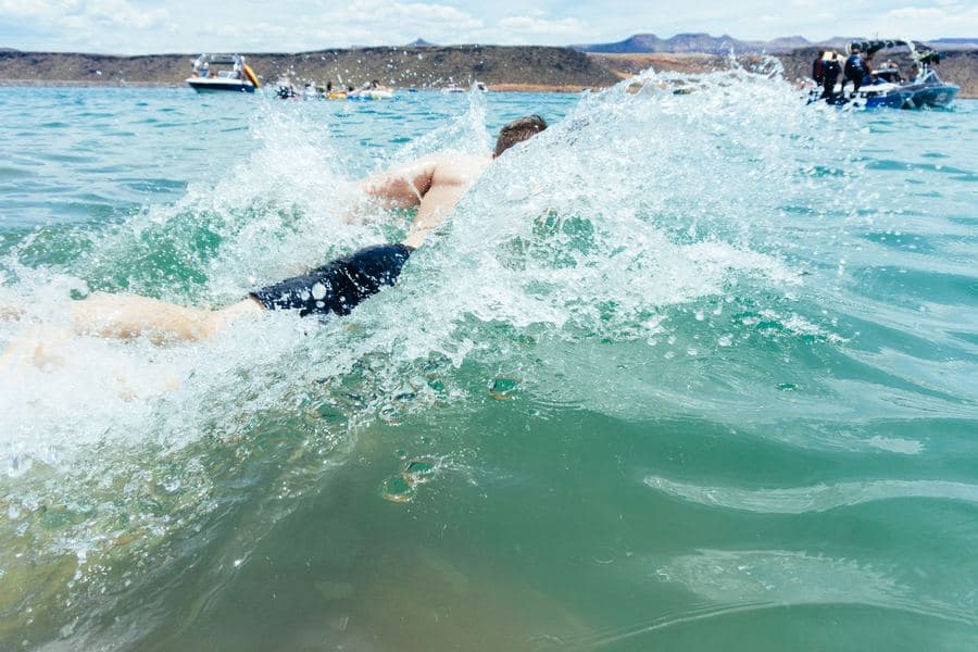Nadador em águas abertas, com barcos ao fundo